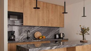 A modern kitchen with wooden cabinets, a marble countertop, a built-in oven, and two bar stools.