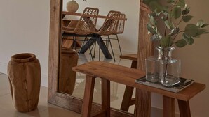 Un grand miroir à cadre en bois, avec une table en bois et un vase placés devant.