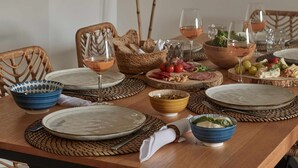 Une table à manger dressée avec des assiettes, des bols, des verres et un centre de table.