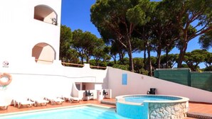 Zona de piscina con jacuzzi, sillas de descanso y un muro de piedra.