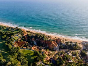 Luchtbeeld van een kustgebied met een strand, kliffen en een golfbaan.