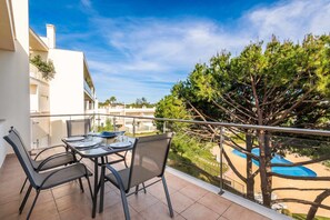 Un balcone con tavolo e sedie, con vista su una piscina e un albero.
