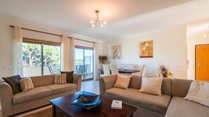 A modern living room with two sofas, a coffee table, and a dining area with chairs. - Balaia Residence 2 Bedroom Penthouse With Pool (Albufeira)