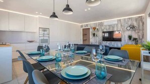 Een moderne eetruimte met een glazen tafel, blauwe borden en zwarte stoelen.