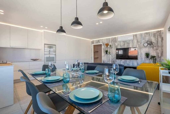 A modern dining area with a glass table, blue plates, and black chairs.