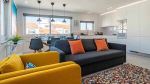 Een moderne woonkamer met een bank, gele fauteuils en een eethoek met een tafel en stoelen.