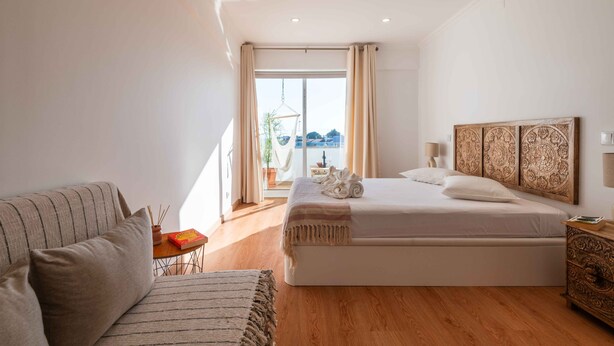 A bedroom with a bed, a sofa, a small table, and a nightstand. - Montechoro Sea View 3 Bedroom Apartment (Albufeira)