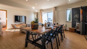 A modern kitchen with a wooden table, chairs, a TV, and a stone backsplash. - Montechoro Sea View 3 Bedroom Apartment (Albufeira)