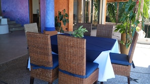 Un'area pranzo all'aperto con sedie in vimini e un tavolo ricoperto da una tovaglia blu.