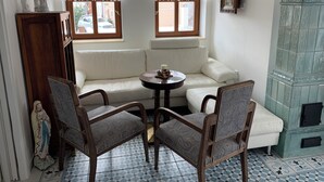 Une pièce d’angle avec un canapé blanc, deux fauteuils à motifs, une petite table ronde avec une bougie et un meuble décoratif.