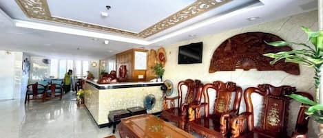 A hotel lobby with a reception desk, seating area, and a decorative ceiling.