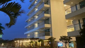 A multi-story hotel with a modern design, featuring balconies and a central atrium with lighting.