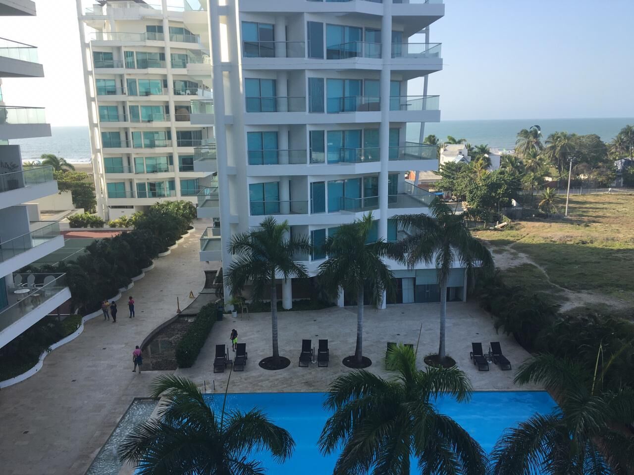 A hotel with a pool, palm trees, and a view of the ocean.