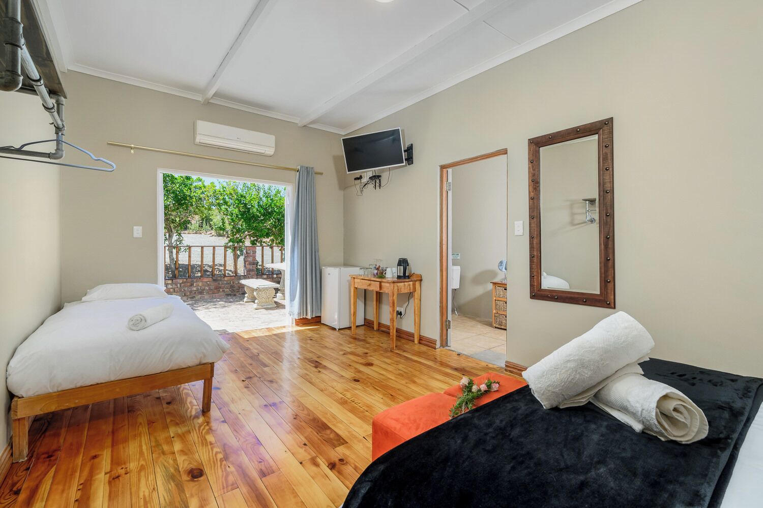 A room with two beds, a TV, a mirror, and a small table with a coffee maker.
