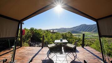 Una terraza al aire libre con una mesa y sillas, con vista a un paisaje montañoso.