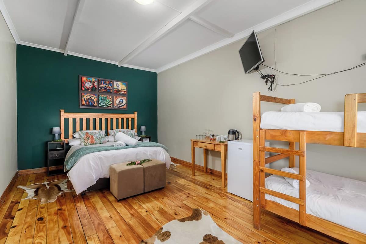 A room with a bed, a desk, a bunk bed, a television, and artwork on the wall.