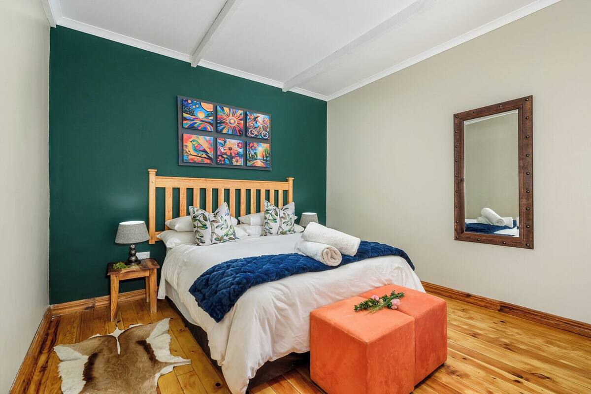 Un dormitorio con una cama de madera, una mesita de noche, un espejo y una pared verde.