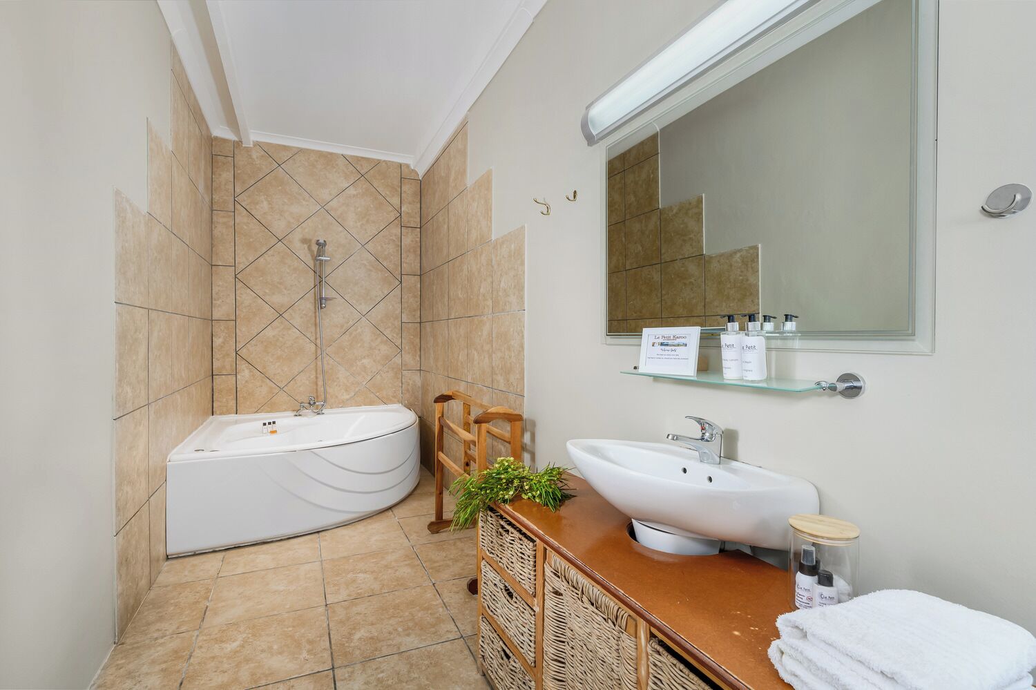 A modern bathroom with a freestanding bathtub, a sink, a mirror, and a glass shelf with toiletries.