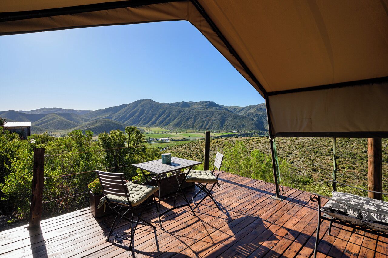 An outdoor deck with a table and chairs, overlooking a mountainous landscape.