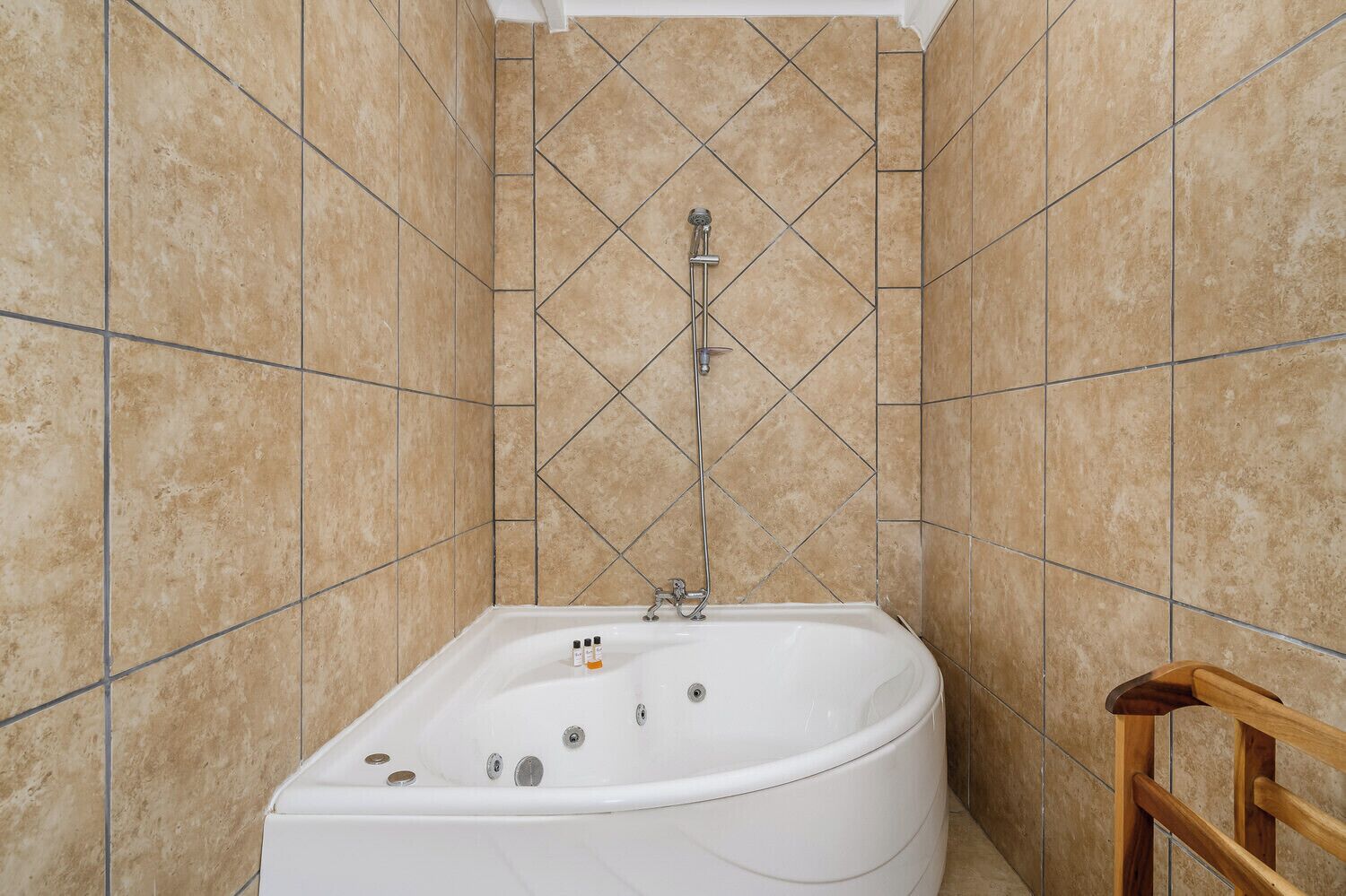 A bathroom with a white bathtub, tiled walls, and a wooden chair.