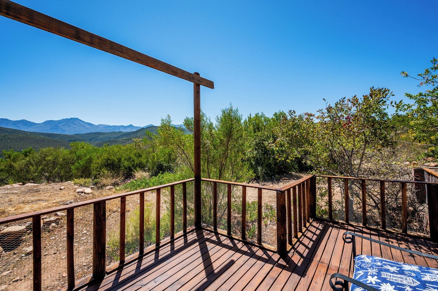 A wooden deck with a view of mountains and greenery.