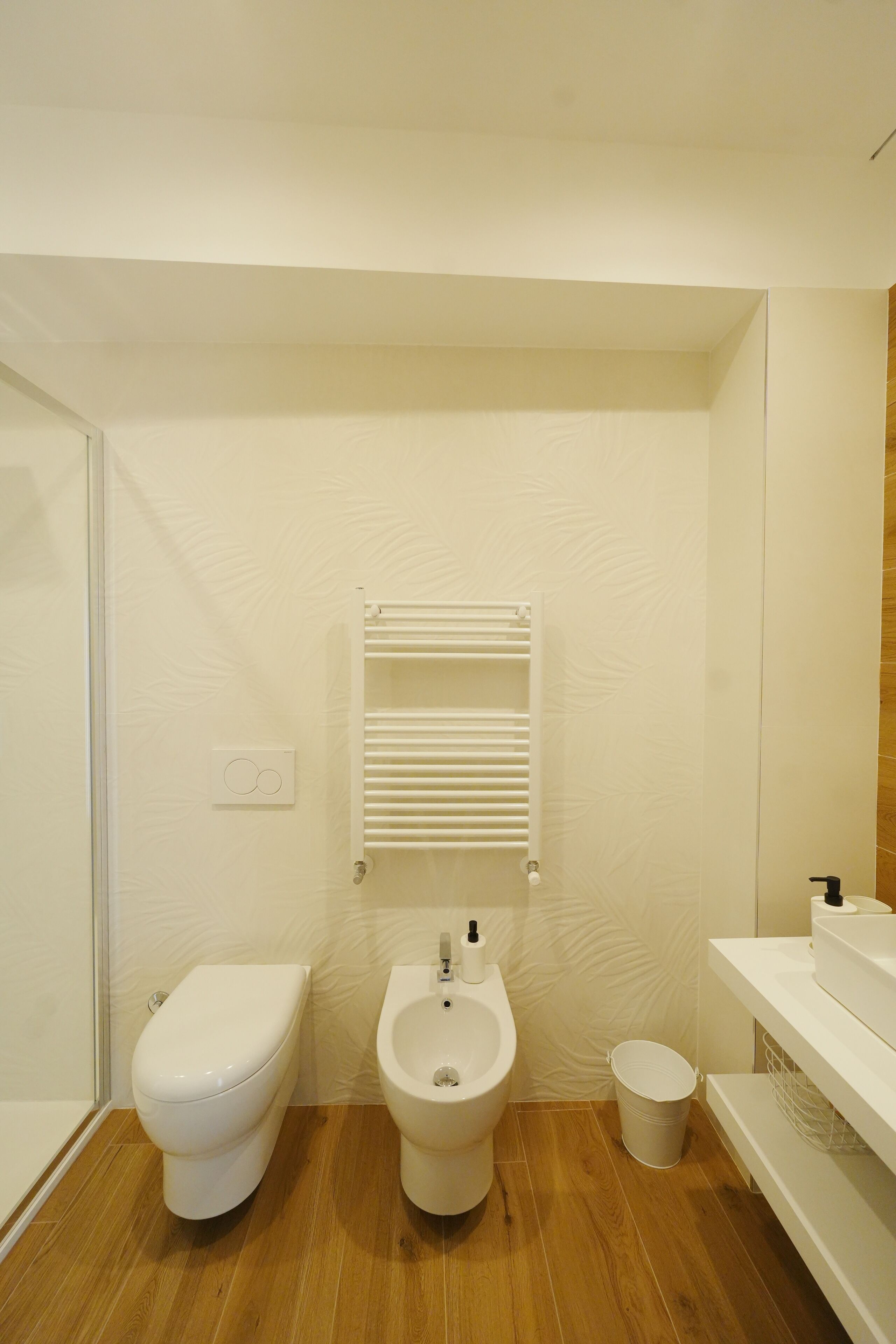 A bathroom with a toilet, bidet, and a small trash bin.