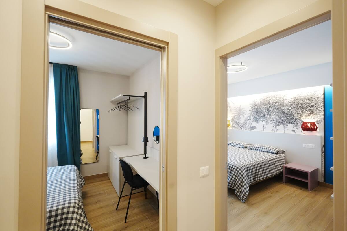 A room with two beds, a desk, a chair, and a mirror.