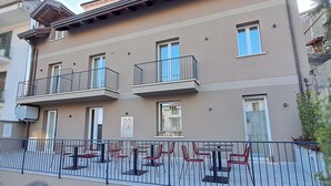Un edificio residenziale a più piani con balconi, una terrazza con sedie e un cartello che indica il numero dell'unità.