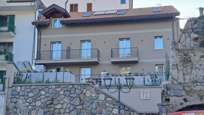 Un edificio a più piani con balconi, gradini in pietra e una targa con il numero civico indicato.
