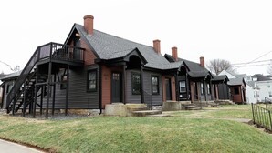 A row of traditional wooden houses with black railings and chimneys.