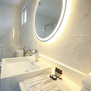 A bathroom with a large mirror, a sink, and toiletries on the counter.