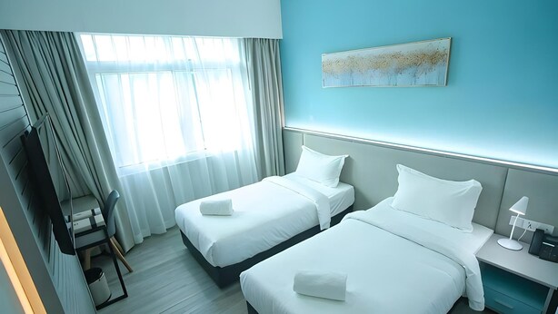 Habitación de hotel con dos camas, un escritorio, una silla, un televisor y un cuadro en la pared.