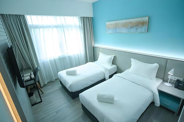 Habitación de hotel con dos camas, un escritorio, una silla, un televisor y un cuadro en la pared.