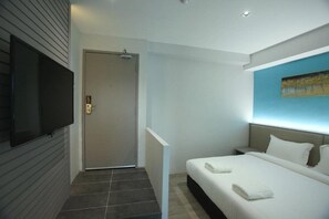A modern hotel room with a bed, a flat-screen TV, a door, and a painting on the wall. - Stanton City Hotel (Kota Kinabalu)