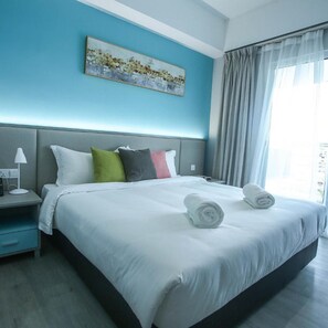 A hotel room with a large bed, a nightstand, a lamp, and a painting on the wall.