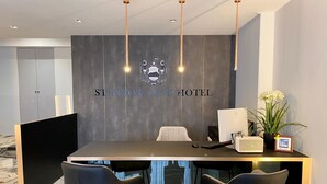 Una recepción con un logotipo, una computadora, un teléfono y dos sillas.