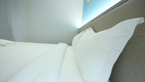 Una cama bien hecha con sábanas blancas en una habitación de hotel.