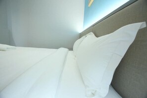 Una cama bien hecha con sábanas blancas en una habitación de hotel.