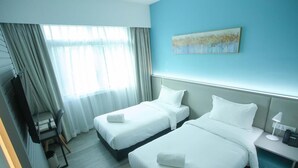 Una habitación de hotel con dos camas, un escritorio con lámpara y un cuadro en la pared.