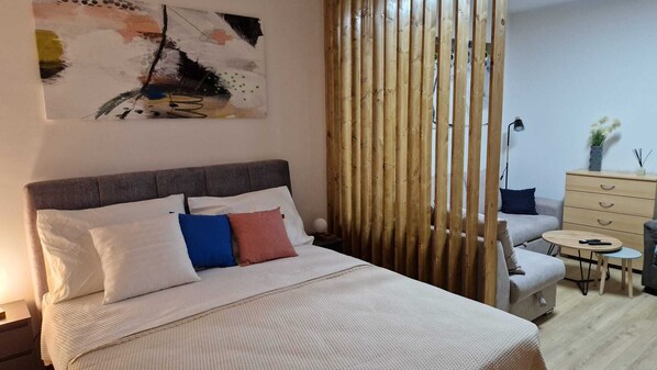 Un dormitorio con cama, mesitas de noche, cómoda, una pequeña mesa redonda y una silla.