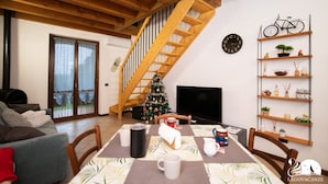 Una sala de estar acogedora con una escalera de madera, un árbol de Navidad y una estantería con varios objetos.