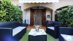 Un patio con mobiliario de mimbre, una mesa con un centro de mesa floral y una entrada cubierta.
