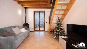 Una sala de estar con escaleras de madera, un sofá, un televisor y un árbol de Navidad.