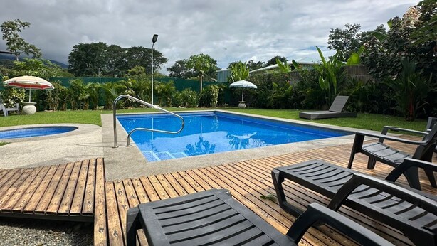 Una piscina con muelle de madera y sillones de descanso.