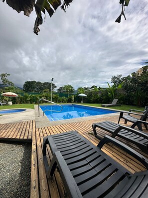 A swimming pool with wooden deck and lounge chairs. - Sueños de maria (Bahía Ballena)