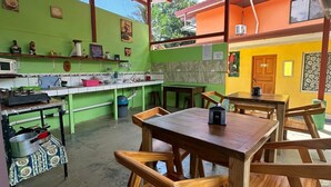 Una cocina rústica con muebles de madera, pared verde y techo de lámina corrugada.