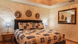 Ein Schlafzimmer mit einem großen Bett, zwei Nachttischlampen, einem Kopfteil und drei Wandbildern.