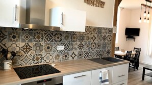 A modern kitchen with a patterned backsplash, stainless steel appliances, and a wooden countertop.