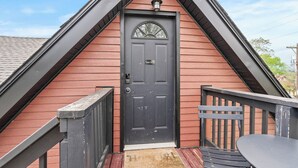 A red wooden house with a black door, a small porch, and a bench.