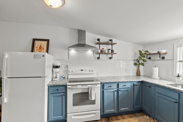 Una cocina con electrodomésticos blancos, armarios azules y encimera de granito.